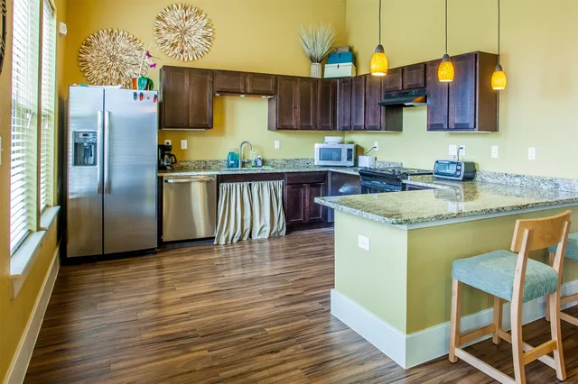 a kitchen with stainless steel appliances granite countertop a refrigerator a sink dishwasher a microwave oven with granite countertops and cabinets