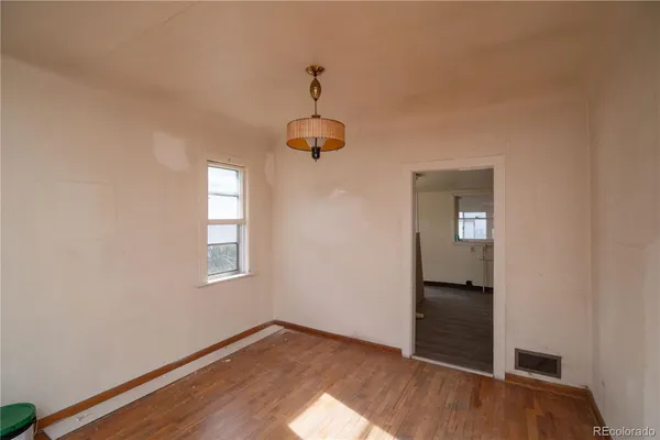 an empty room with wooden floor cabinet and windows