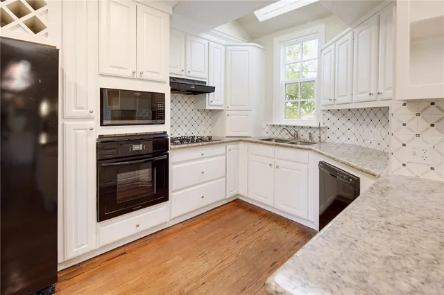 a kitchen with granite countertop wooden cabinets stainless steel appliances and a window