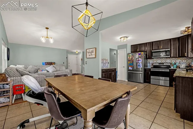 a living room with stainless steel appliances kitchen island granite countertop a dining table chairs sink and dishwasher