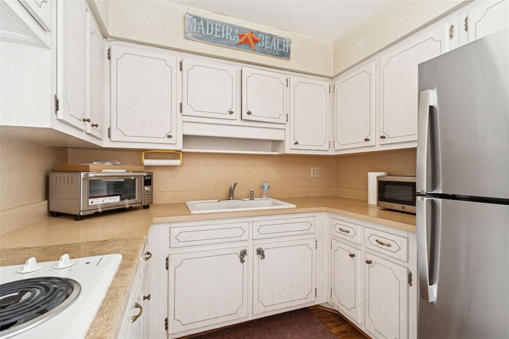 4565 Duhme Road, Unit 203 St. Petersburg, FL 33708 - Photo 9 of 27 a kitchen with stainless steel appliances white cabinets and a refrigerator