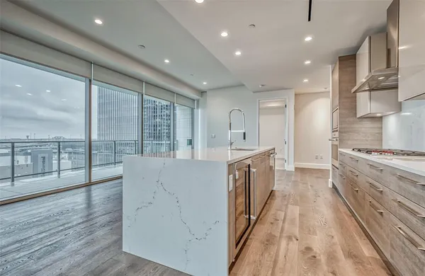a large kitchen with stainless steel appliances a large counter top a stove and a wooden floors