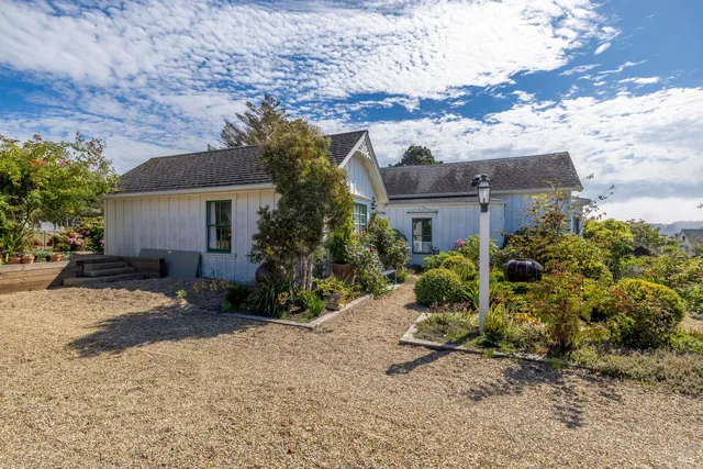 front view of house with a bench and potted plants