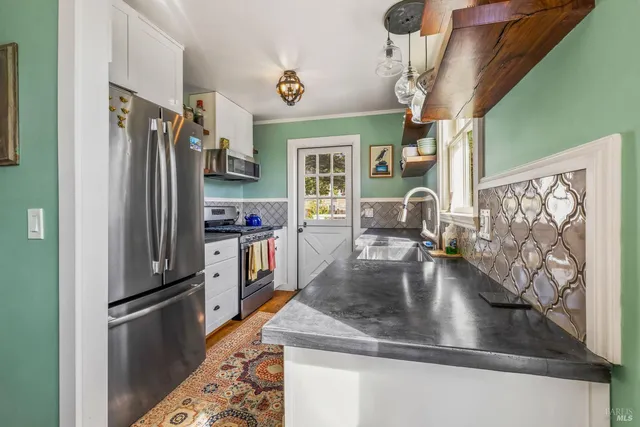 a kitchen with stainless steel appliances granite countertop a refrigerator a stove and a sink with wooden floor