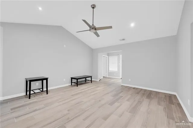 a view of an empty room with window and wooden floor