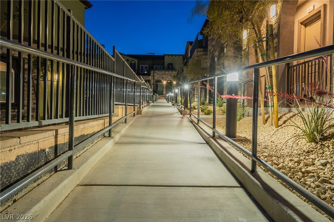 6444 Spring Jog Street Las Vegas, NV 89166 - Photo 5 of 13 This outdoor pathway is illuminated by stylish light fixtures, guiding residents along the building's exterior.