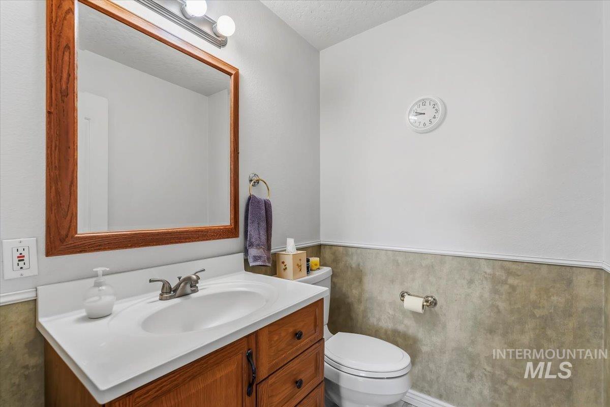 2331 Gulley Road Homedale, ID 83628 - Photo 23 of 46 Bathroom featuring a wood-finish vanity with an integrated sink and brushed nickel faucet, a large mirror with a wood-finish frame, and light-toned walls with a lower wainscoting detail