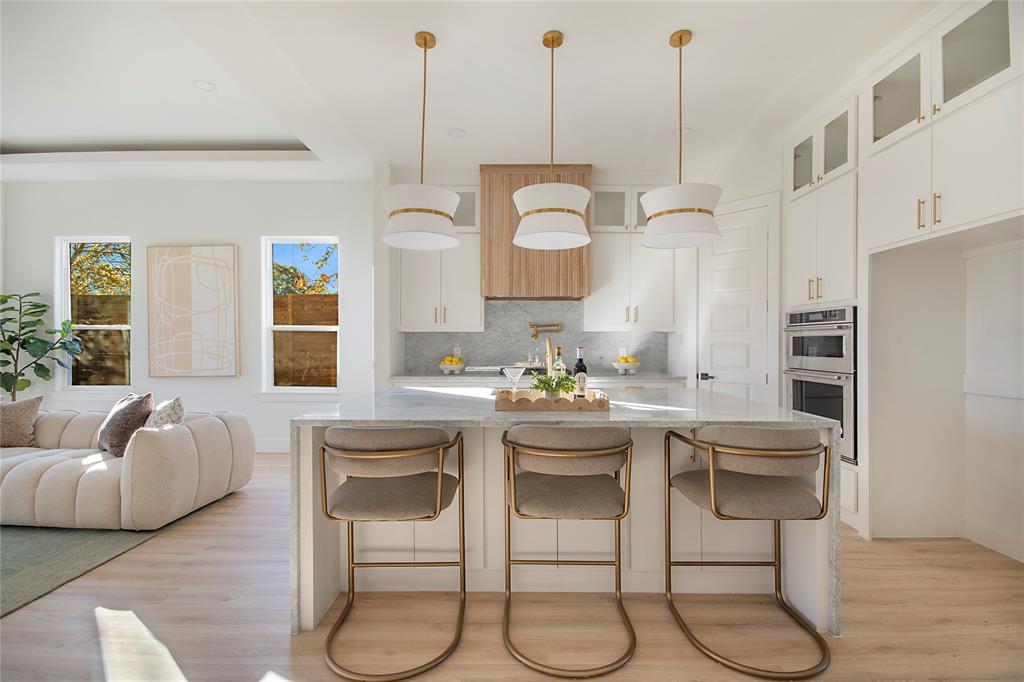 Kitchen featuring white cabinetry, a kitchen bar, decorative light fixtures, and light wood finished floors