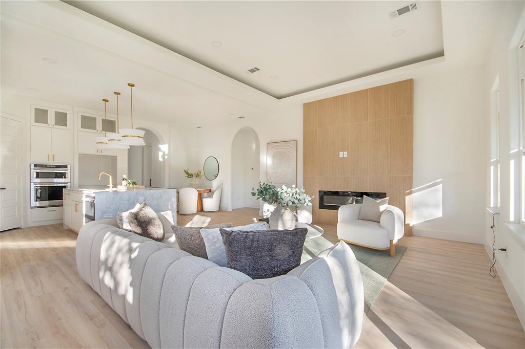 3902 Furey Street Dallas, TX 75212 - Photo 9 of 34 Living area featuring a tray ceiling, a large fireplace, light wood finished floors, and arched walkways