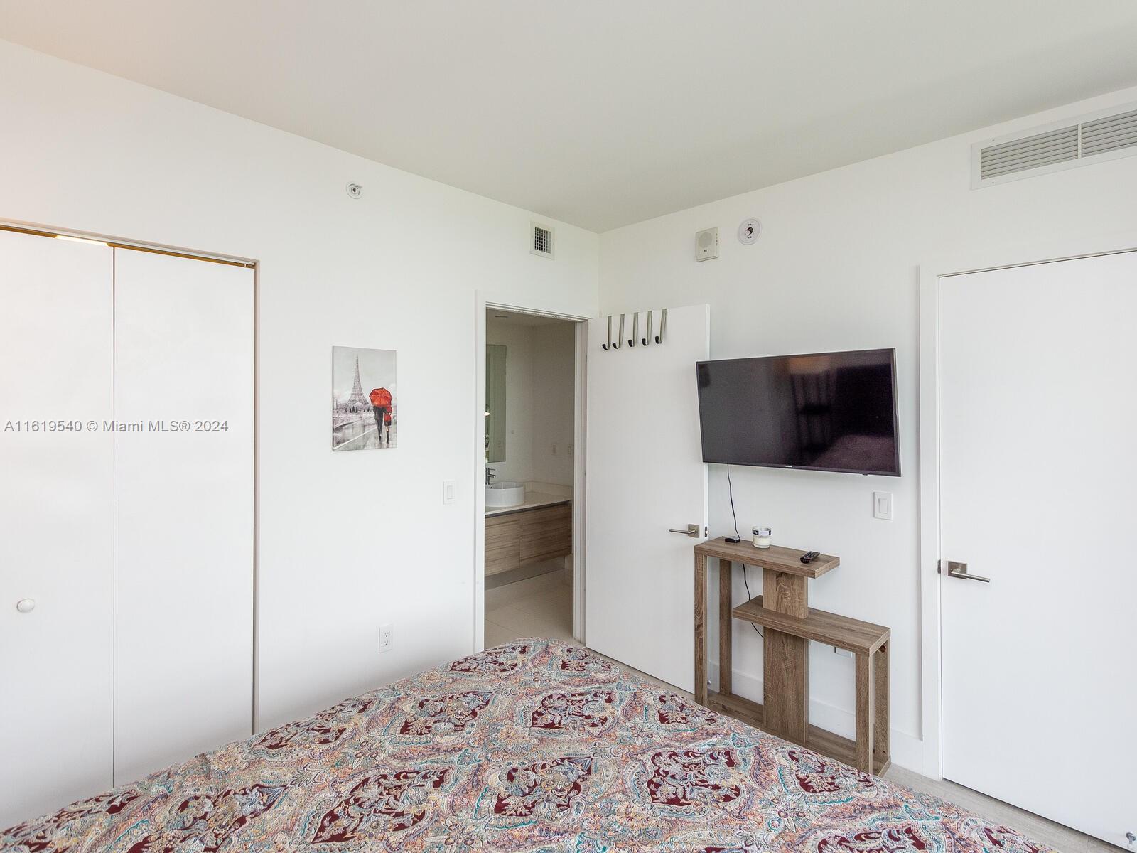 121 Northeast 34th Street, Unit 1014 Miami, FL 33137 - Photo 26 of 30 a bedroom with a bed and a television in it