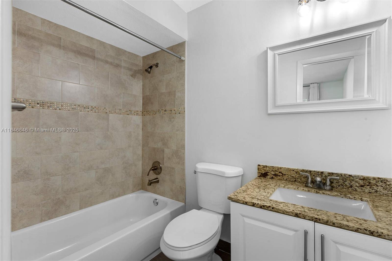 8218 Southwest 82nd Court Miami, FL 33143 - Photo 13 of 20 a bathroom with a granite countertop toilet a sink and a bathtub
