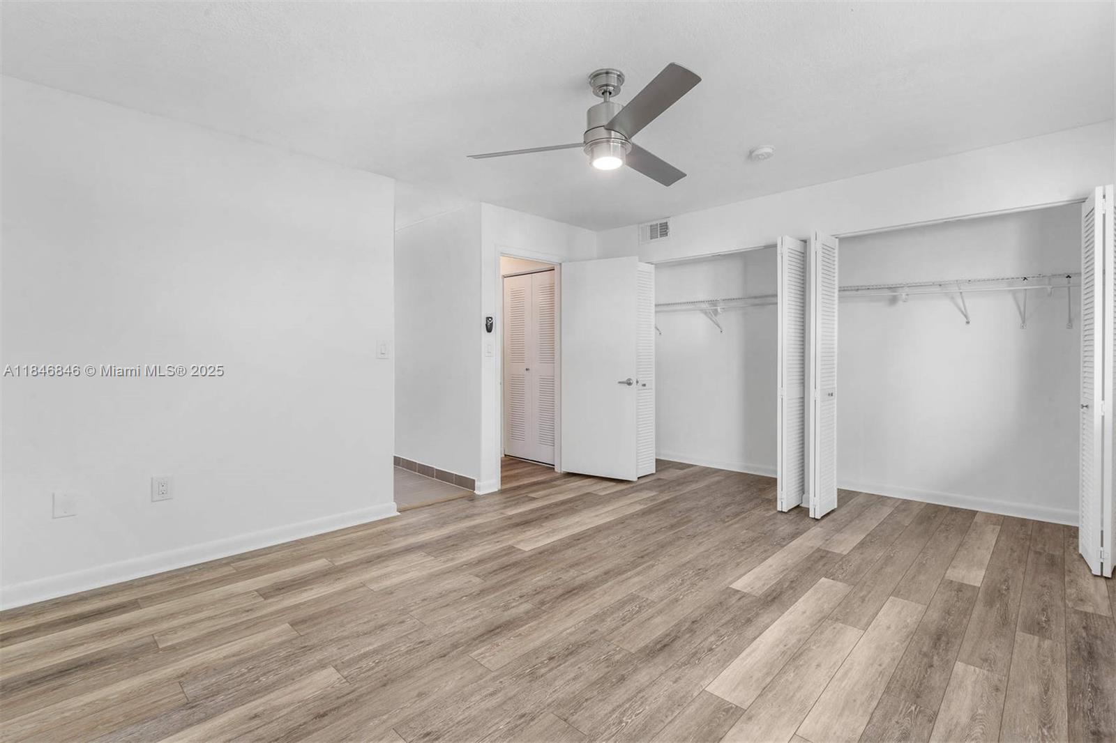 8218 Southwest 82nd Court Miami, FL 33143 - Photo 15 of 20 an empty room with wooden floor ceiling fan and windows