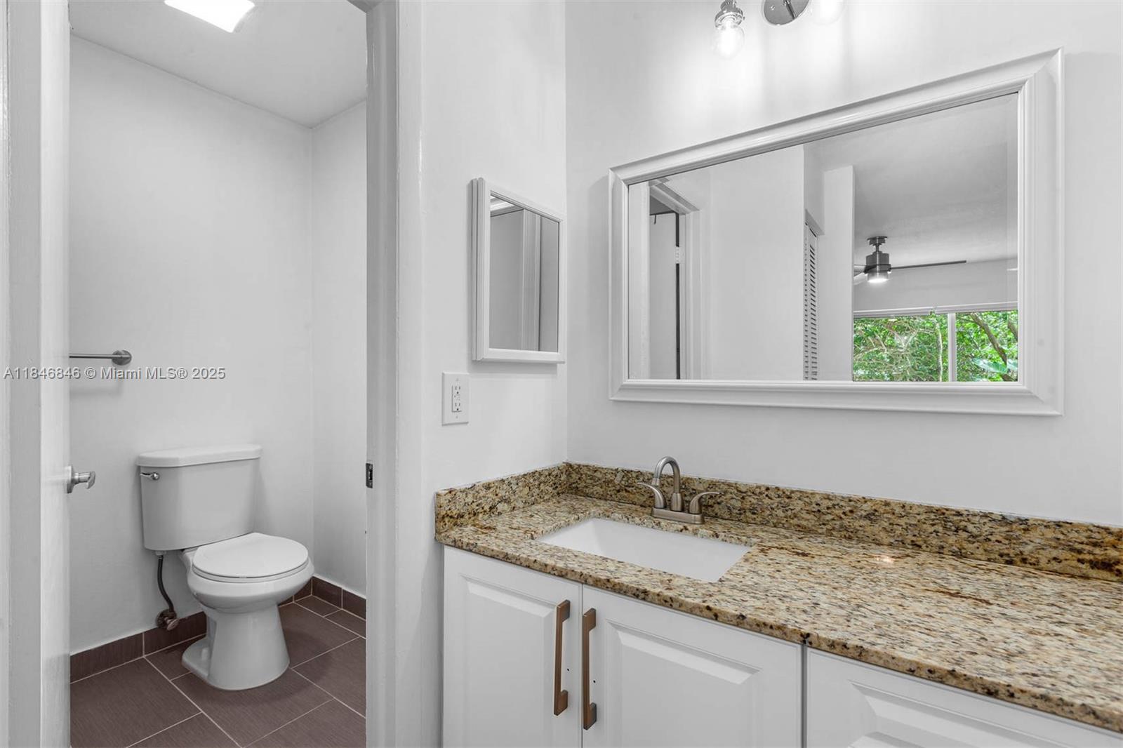 8218 Southwest 82nd Court Miami, FL 33143 - Photo 16 of 20 a bathroom with a granite countertop sink toilet and mirror
