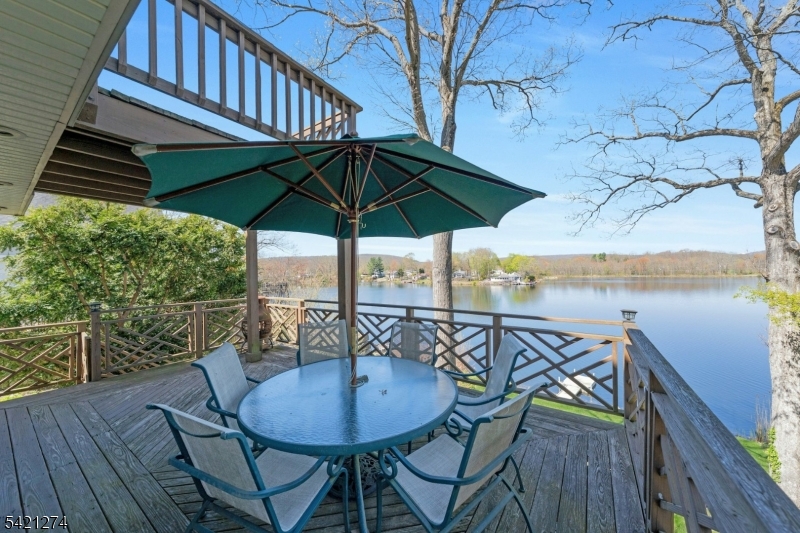 95 Wildwood Road Oak Ridge, NJ 07438 - Photo 16 of 36 a view of a patio with table and chairs under an umbrella with wooden floor