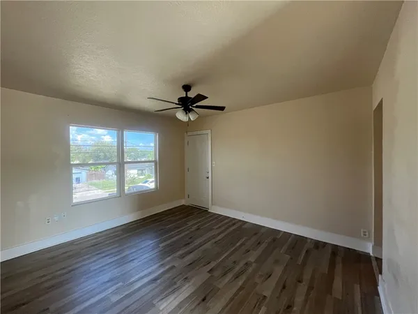 a view of an empty room with wooden floor and a window