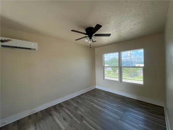 a view of an empty room with a window and wooden floor