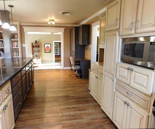 a large space with wooden floor and stainless steel appliances