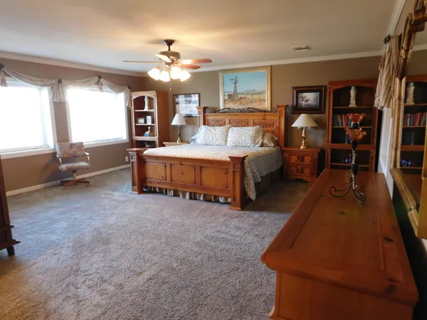 a spacious bedroom with a bed a chandelier and a book shelf