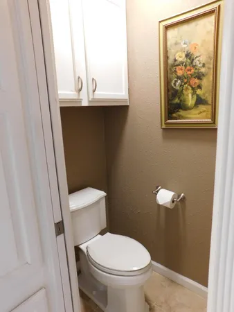 a bathroom with a toilet and a painting on the wall