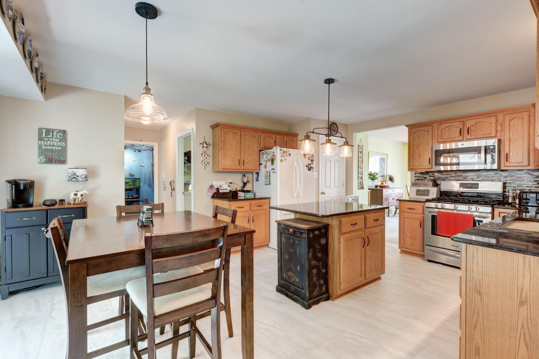20 Union Street Littlestown, PA 17340 - Photo 12 of 58 a kitchen with stainless steel appliances kitchen island granite countertop a table chairs and a refrigerator