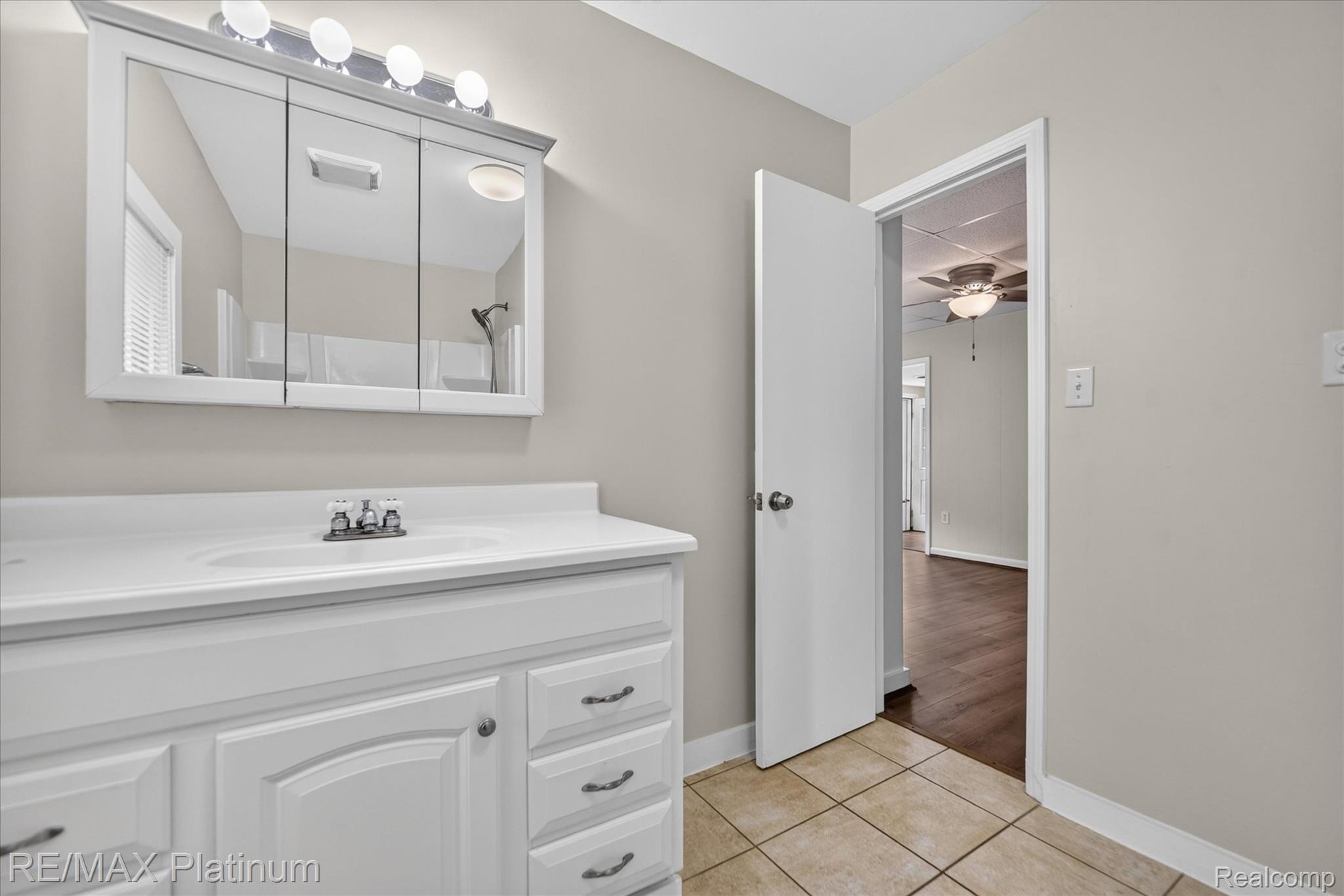 501 Kaiser Road Gregory, MI 48137 - Photo 17 of 27 Bathroom featuring a white vanity with an integrated sink, tri-fold medicine cabinet with overhead lighting, and tile flooring