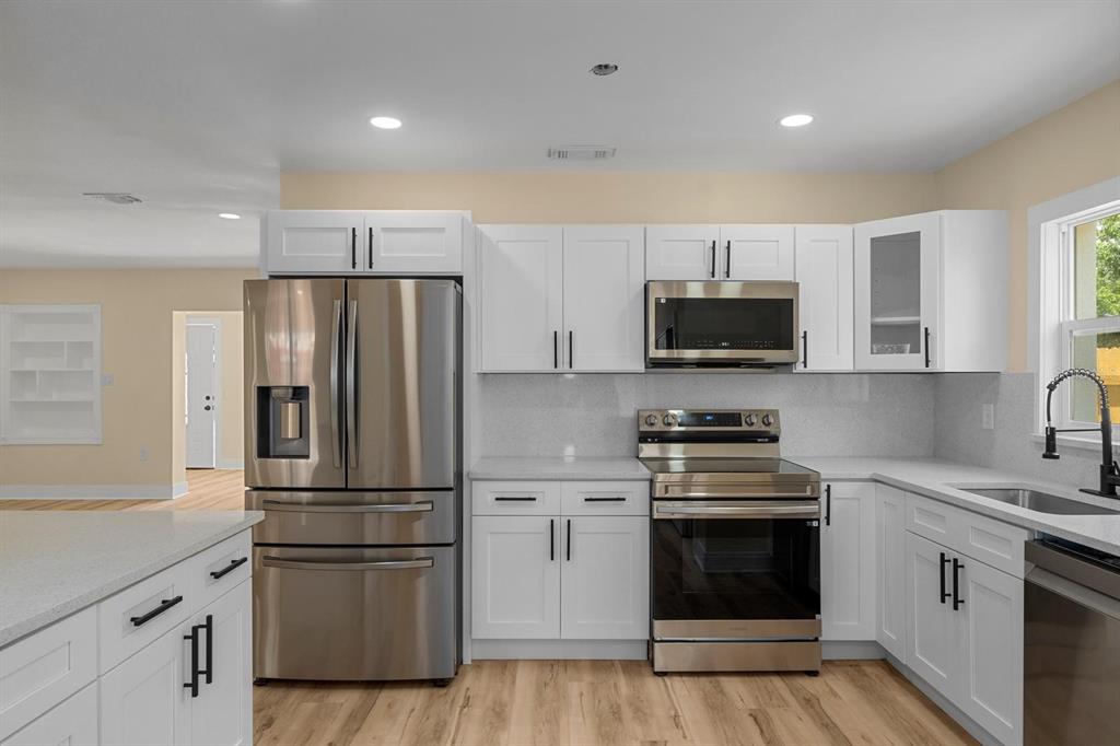 10707 North Rome Avenue Tampa, FL 33612 - Photo 27 of 35 a kitchen with cabinets stainless steel appliances and wooden floor