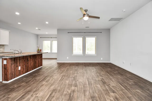 a view of an empty room with window and wooden floor