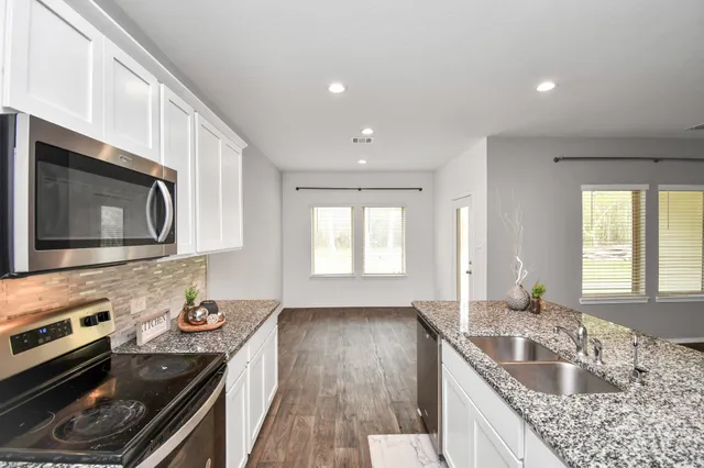 a kitchen with granite countertop stainless steel appliances a stove sink and microwave