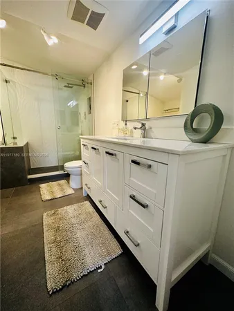 a en suite bathroom with a granite countertop sink and a mirror
