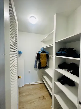a view of walk in closet with clothes and shoes