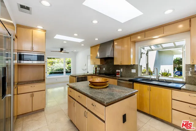 a kitchen with granite countertop kitchen island stainless steel appliances a sink a counter top space and living room view