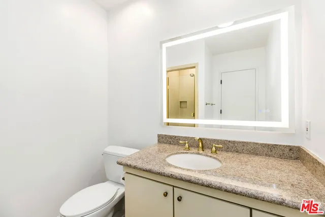 a bathroom with a granite countertop toilet sink and mirror