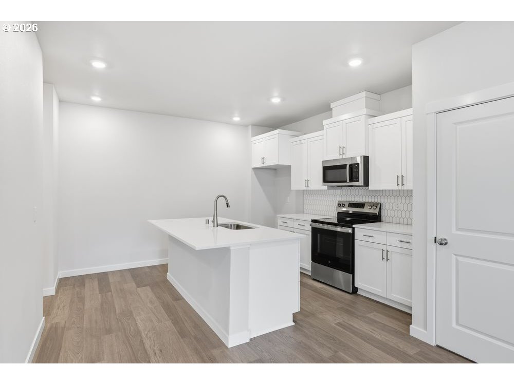 444 Southwest 32nd Street Battle Ground, WA 98604 - Photo 3 of 13 a kitchen with stainless steel appliances a sink a stove a microwave a center island and cabinets