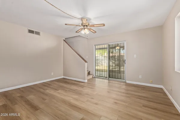 an empty room with wooden floor fan and windows
