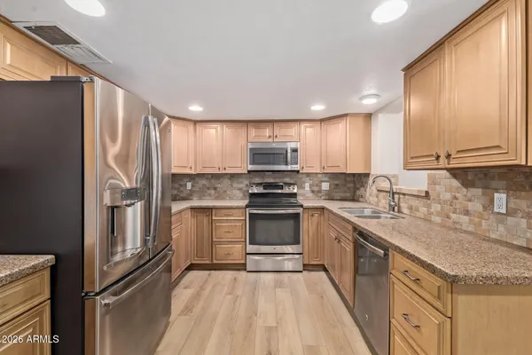 a kitchen with stainless steel appliances granite countertop a refrigerator stove and wooden cabinets