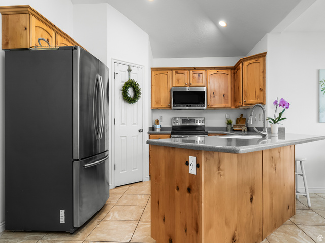 1602 Renaissance Way Springville, UT 84663 - Photo 12 of 42 Kitchen featuring knotty pine cabinetry, a central island with an integrated sink, stainless steel appliances, and a tiled floor