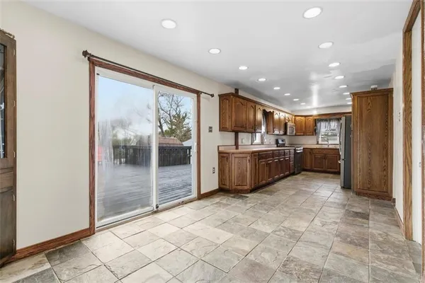 a large kitchen with a large counter top a sink stainless steel appliances and cabinets