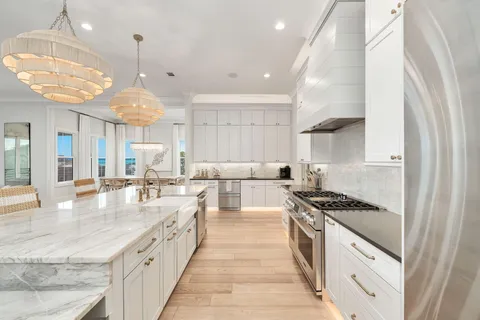 a large kitchen with stainless steel appliances a large counter top a stove a chimney a sink and a refrigerator