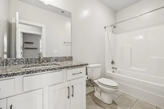 a bathroom with a granite countertop toilet sink and a mirror