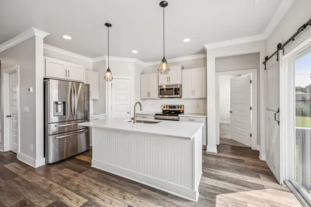 a kitchen with stainless steel appliances kitchen island granite countertop a refrigerator a oven and a sink