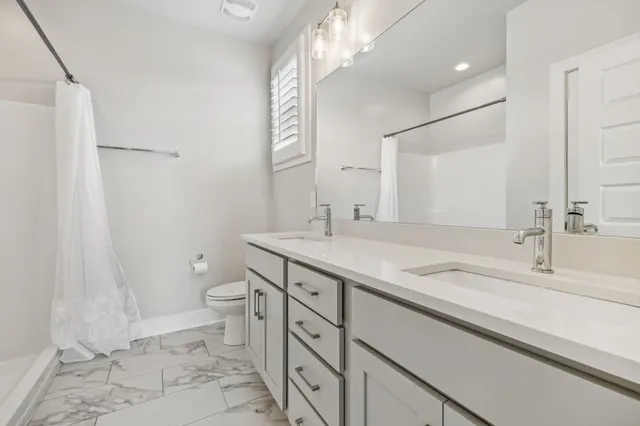 a bathroom with a granite countertop sink a toilet and a mirror