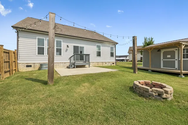 a view of a small house with a small yard and wooden fence