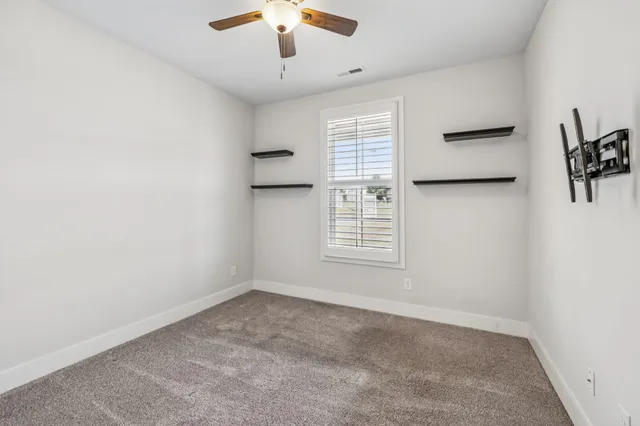 en empty room with windows and ceiling fan