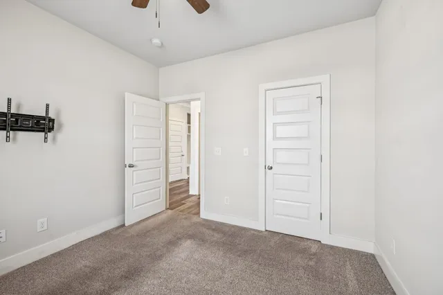 an empty room with closet and a ceiling fan