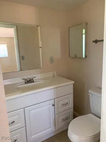 a bathroom with a toilet sink vanity and mirror
