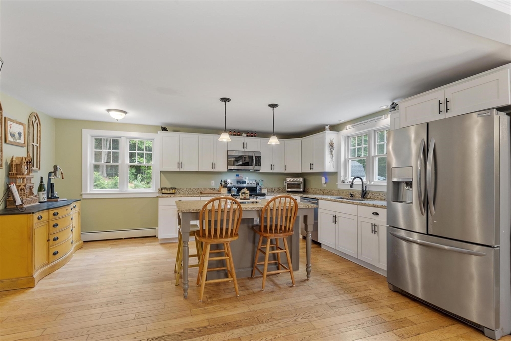 241 Reservoir Road Lunenburg, MA 01462 - Photo 4 of 40 a kitchen with stainless steel appliances a refrigerator a stove a sink dishwasher and a dining table with wooden floor