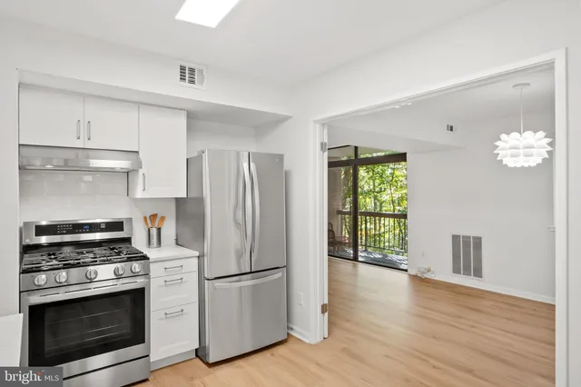a kitchen with a refrigerator stove and wooden floor