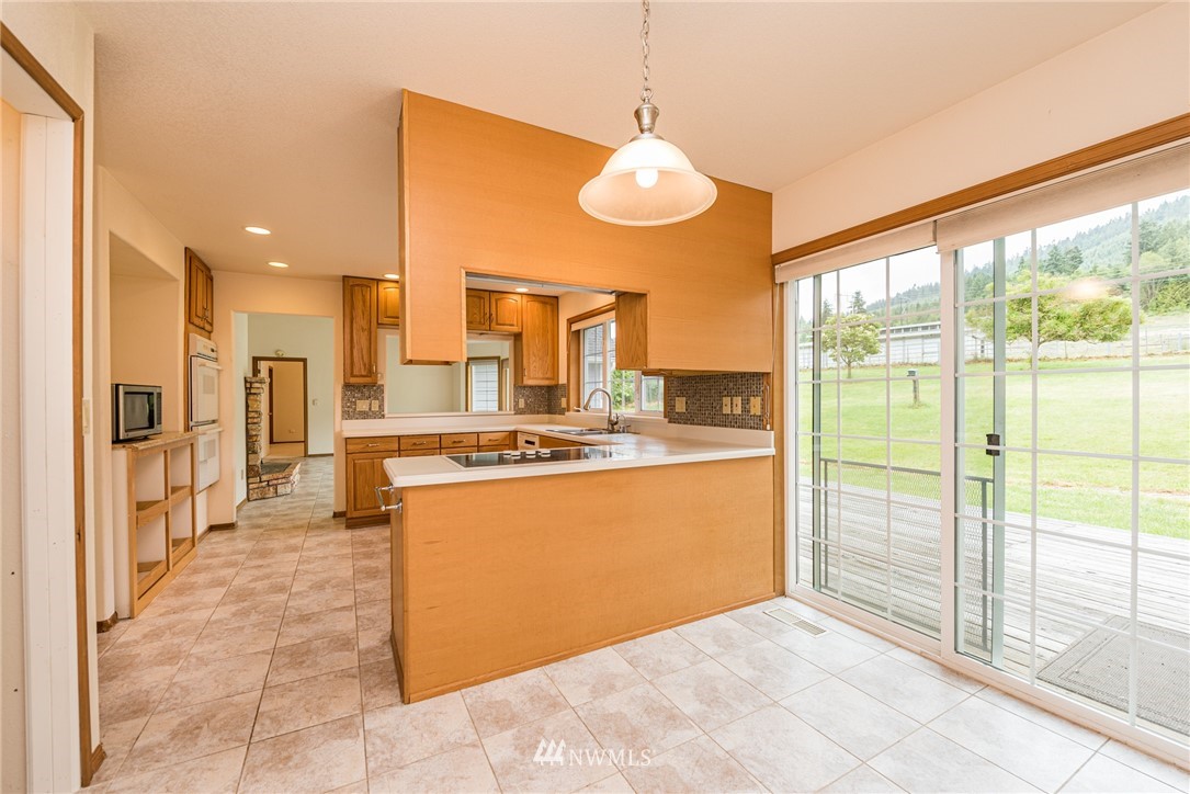 2367 Happy Valley Road Sequim, WA 98382 - Photo 8 of 39 a view of a kitchen with kitchen island a large window cabinets a sink and stainless steel appliances