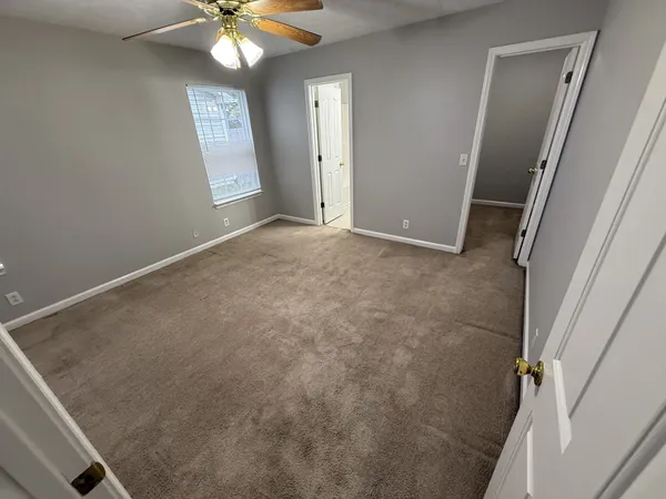 an empty room with windows and fan