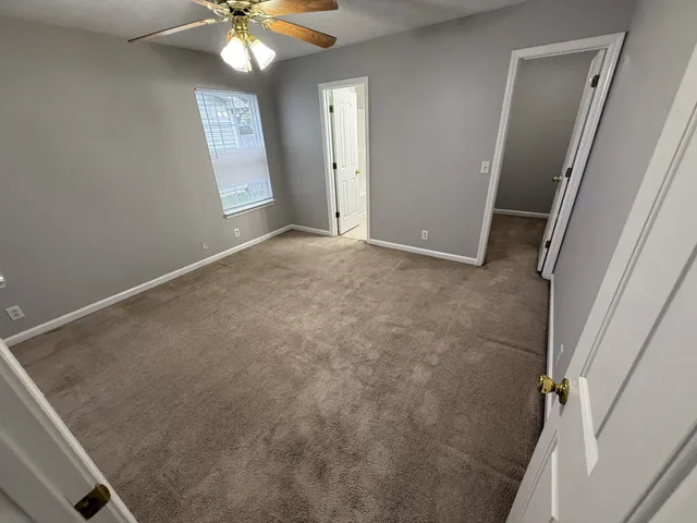 an empty room with windows and fan